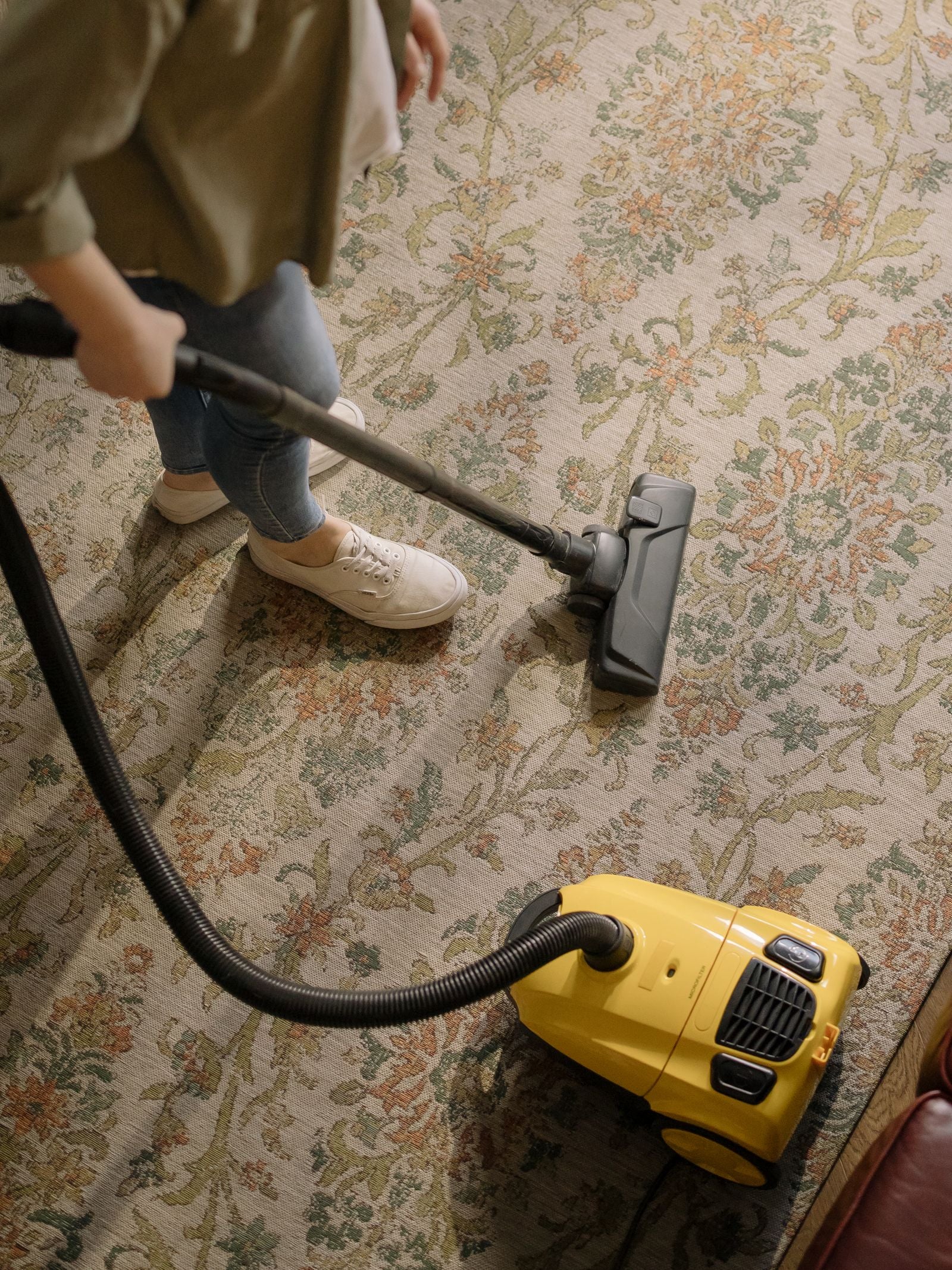 A person vacuuming a patterned area rug
