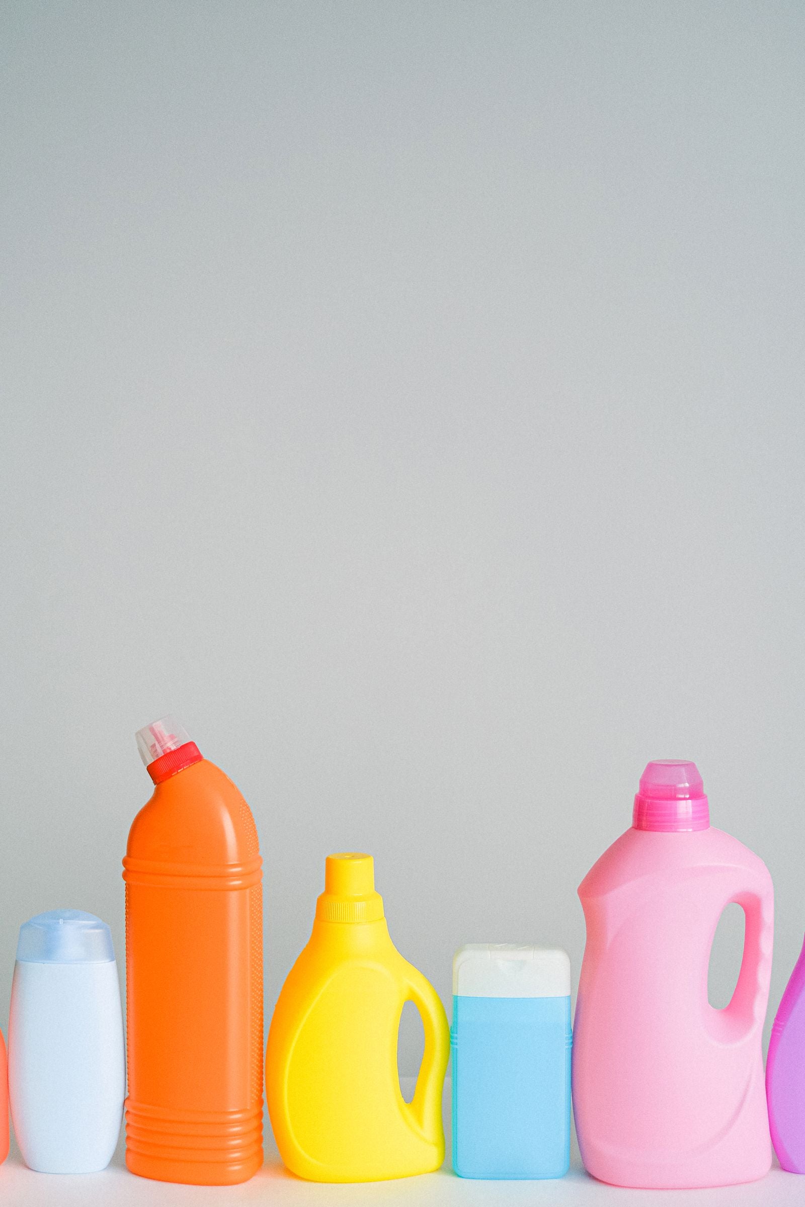 A row of unbranded cleaning solution bottles against a plain background