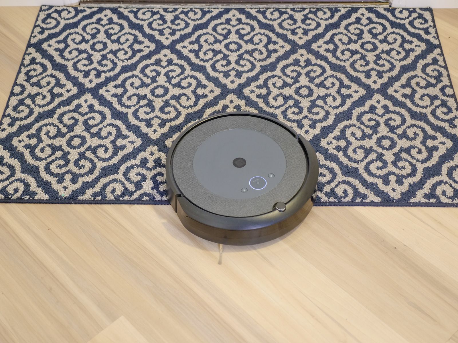 A robot vacuum crossing from hardwood onto a patterned carpet
