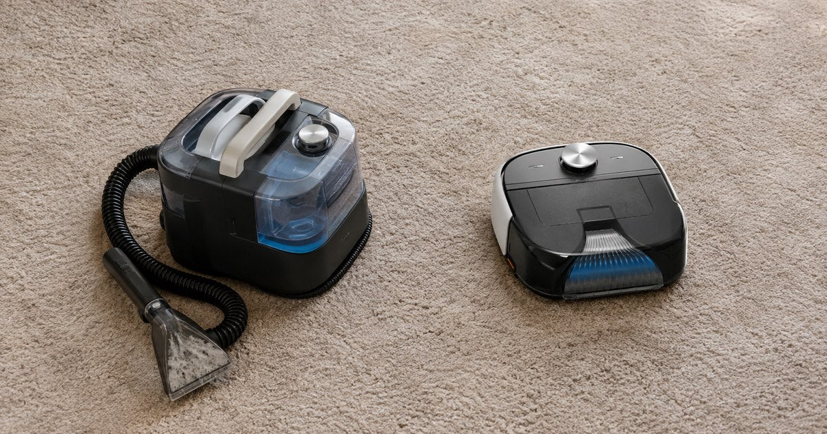 A compact portable spot carpet cleaner with hose and hand tool beside a low square robot carpet washer on the same carpet, showing the size difference